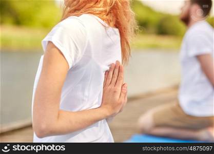 fitness, sport, yoga and healthy lifestyle concept - group of people exercising in reverse prayer pose on river or lake berth