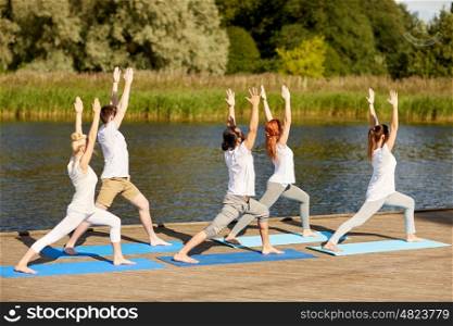 fitness, sport, yoga and healthy lifestyle concept - group of people making high lunge or crescent pose on river berth