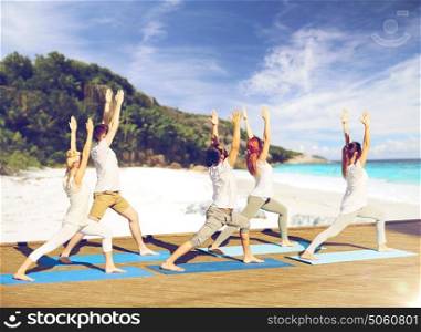 fitness, sport, yoga and healthy lifestyle concept - group of people making high lunge or crescent pose over exotic tropical beach and sea shore background. group of people making yoga exercises on beach
