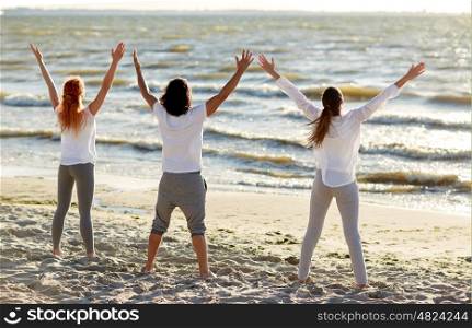 fitness, sport, yoga and healthy lifestyle concept - group of people meditating on beach