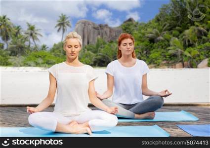 fitness, sport, yoga and people concept - women meditating in lotus pose outdoors. women meditating in yoga lotus pose outdoors