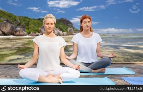 fitness, sport, yoga and people concept - women meditating in lotus pose outdoors. women meditating in yoga lotus pose outdoors