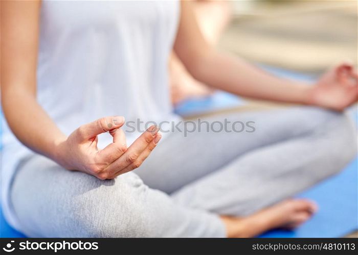 fitness, sport, yoga, people and healthy lifestyle concept - close up of woman meditating in easy sitting pose