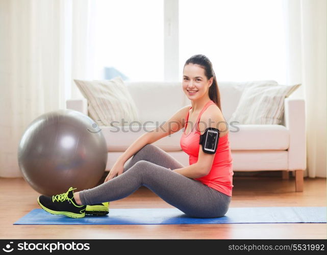 fitness, sportm home and dieting concept - smiling teenage girl with armband execising at home