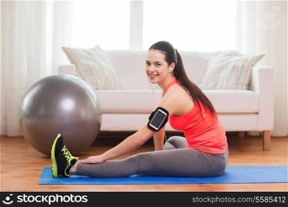 fitness, sportm home and dieting concept - smiling teenage girl with armband execising at home