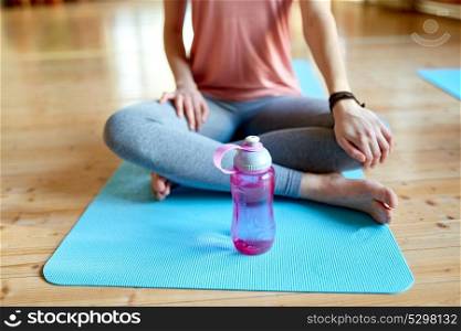 fitness, sports accessories and healthy lifestyle concept - woman with water bottle resting on yoga mat in gym or studio. woman with water bottle resting on yoga mat in gym