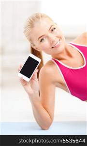 fitness, technology, advertiding and exercise concept - smiling woman lying on the floor and sowing smartphone blank black screen