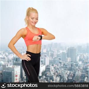 fitness, technology and exercising concept - smiling woman looking at heart rate monitor on hand