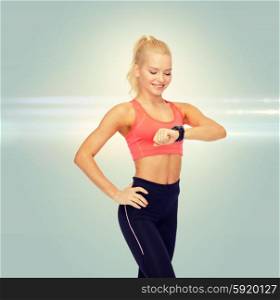 fitness, technology and exercising concept - smiling woman looking at heart rate monitor on hand