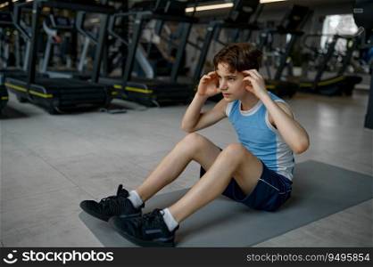 Fitness teenage boy exercising doing crunches for abs muscles building. Indoors workout at gym. Fitness teenage boy exercising doing crunches for abs muscles building