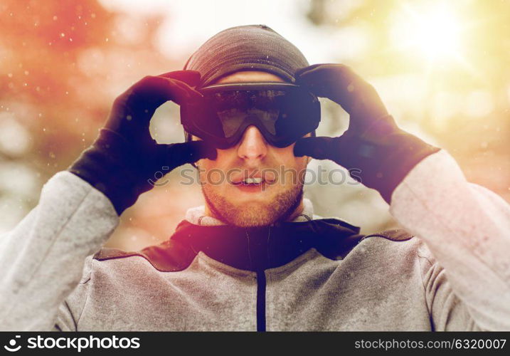 fitness, winter sport, people and healthy lifestyle concept - young man in ski goggles outdoors. sports man with ski goggles in winter outdoors