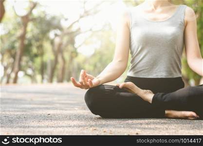Fitness woman are meditating on the streets in the park, in the midst of nature, and the morning sun is shining, focusing on her hands.