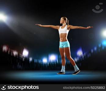 Fitness woman. Fitness woman standing against stadium lights background