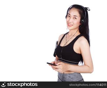 fitness woman listening to music with earphones while standing and using mobile phone isolated on a white background