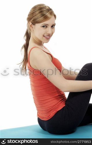 fitness woman making a break. fitness woman sitting on a blue mat making a break on white background