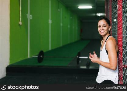 Fitness woman relaxing after workout lean by a fence