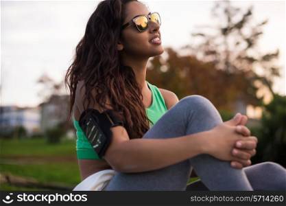 Fitness woman runner relaxing in the city park