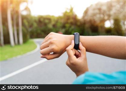 fitness woman runner setting up smart watch before running. Outdoor exercise activities