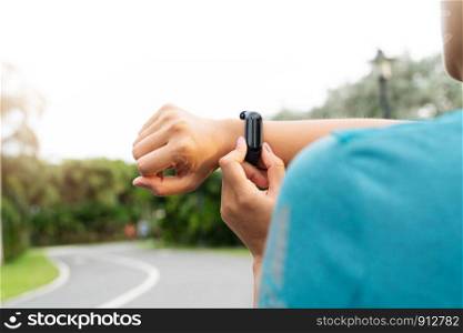 fitness woman runner setting up smart watch before running. Outdoor exercise activities