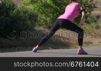 Fitness woman runner stretching before run on the road