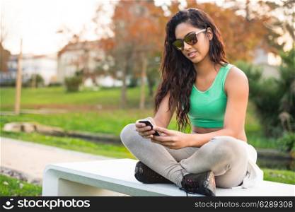 Fitness woman with smartphone at city park