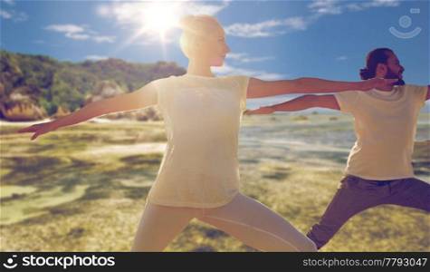 fitness, yoga and healthy lifestyle concept - group of man and woman making warrior pose over tropical beach background. man and woman making yoga exercises on beach