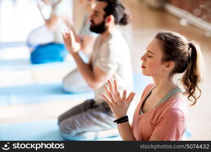 fitness, yoga and healthy lifestyle concept - group of people doing lotus seal gesture and meditating in seated pose at studio. group of people meditating at yoga studio