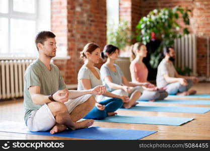 fitness, yoga and healthy lifestyle concept - group of people meditating in lotus pose at studio. group of people making yoga exercises at studio. group of people making yoga exercises at studio