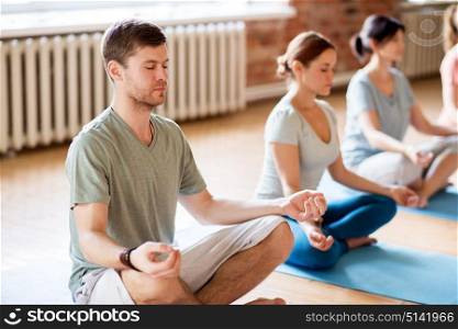 fitness, yoga and healthy lifestyle concept - group of people meditating in lotus pose at studio. group of people making yoga exercises at studio