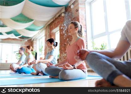 fitness, yoga and healthy lifestyle concept - group of people meditating in lotus pose at studio. group of people meditating at yoga studio