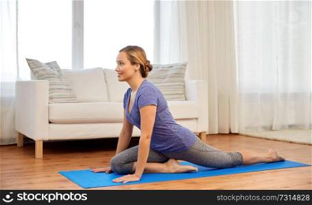 fitness, yoga and healthy lifestyle concept - woman doing swan yin pose on mats at home. woman doing swan yin yoga pose at home