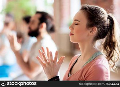 fitness, yoga and healthy lifestyle concept - woman with group of people doing lotus seal gesture and meditating in seated pose at studio. woman with group meditating at yoga studio. woman with group meditating at yoga studio