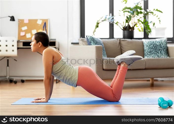fitness, yoga and healthy lifestyle concept - young african american woman doing push-ups at home. african woman doing push-ups at home
