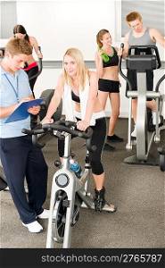 Fitness young girls at gym bicycle with instructor doing spinning