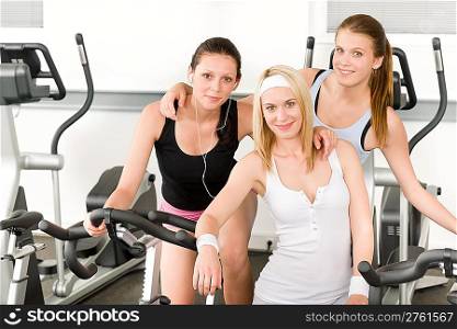 Fitness young girls on gym bike indoor cardio exercise posing