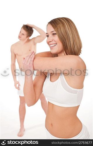Fitness - Young healthy couple stretching after training on white