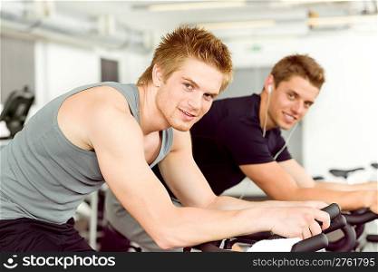 Fitness young man on gym bike spinning indoor cardio exercise