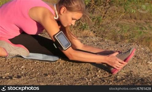Fitness young woman stretching legs before exercise outdoors