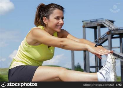 fitness young woman stretching legs in a park in summer
