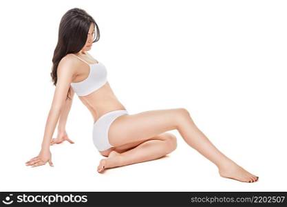 Fitness young woman with a beautiful body sitting on white background.. Fitness young woman with a beautiful body sitting on white background