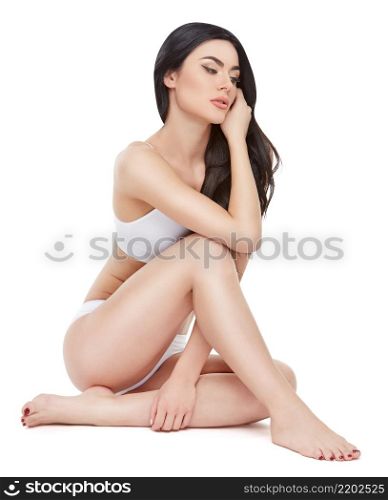 Fitness young woman with a beautiful body sitting on white background.. Fitness young woman with a beautiful body sitting on white background