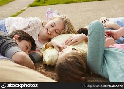 Five boys and girls lying together on path