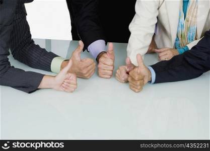 Five business executives showing thumbs up sign in a meeting