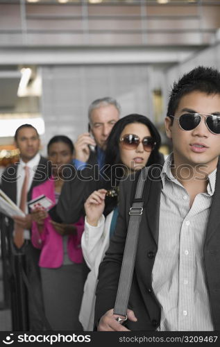 Five business executives standing in a row at an airport