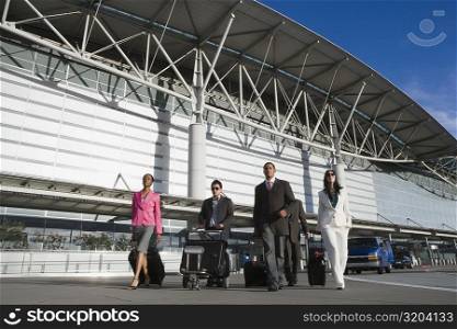 Five business executives walking outside of an airport