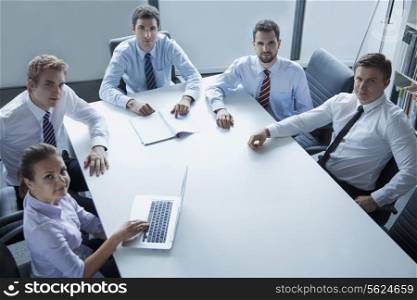 Five business people having a business meeting at the table in the office, looking at camera