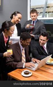 Five business people using laptop in office meeting