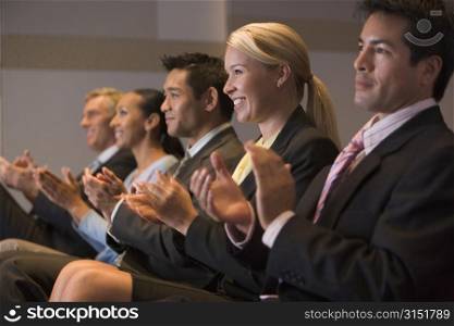 Five businesspeople applauding and smiling in presentation room
