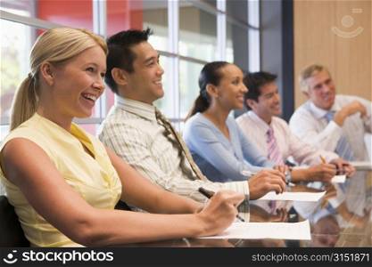 Five businesspeople at boardroom table smiling