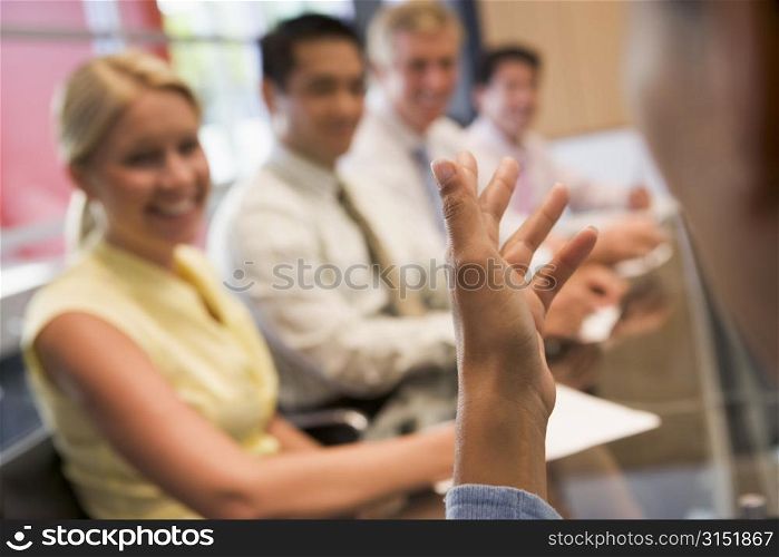 Five businesspeople at boardroom table with focus on businessman&acute;s hand
